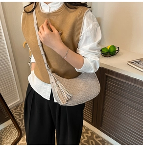 Detail of beige crescent underarm bag with fan pattern embossing and rhinestone tassel