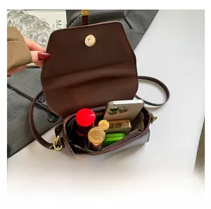 Vue intérieure montrant la capacité du sac marron avec téléphone, rouge à lèvres et poudre