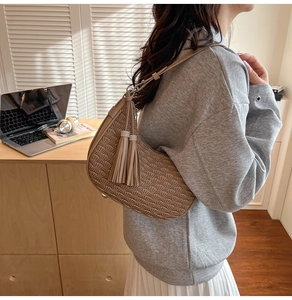 Detail of straw woven baguette bag with shell pleated design and tassel accents