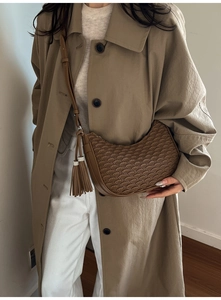 Close-up of brown pleated crescent shoulder bag with leather tassel details on a model