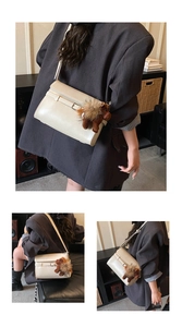 Detail of beige flap crossbody bag with decorative buckle strap and plush horse charm