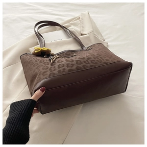 Close-up of leopard print tote bag with leather trim and decorative yellow bow charm