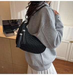 Detail of black pleated hobo bag with rhinestone-embellished tassels and leather texture
