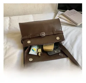 Interior capacity of vintage brown leather shoulder bag showing cosmetics and smartphone