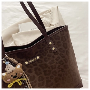 Detail of leopard print tote bag with metal FASHION plaque and plush bear charm