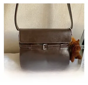 Detailed close-up of retro brown tote bag with silver belt buckle and plush horse charm