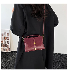 Detail of burgundy crossbody bag with mixed suede and smooth leather on a black coat
