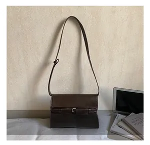 Detailed close-up of dark brown vintage shoulder bag with decorative belt buckle design