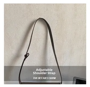 Detail view of the adjustable dark brown leather shoulder strap with a matching leather loop