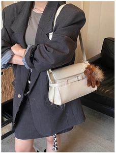 Detail of cream white leather tote bag with a belt buckle and brown horse charm