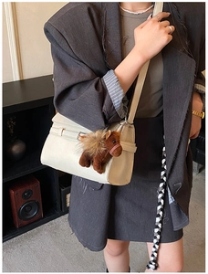 Chic beige shoulder bag with decorative strap and brown plush pony charm detail