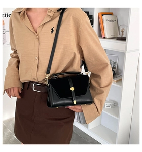 Detailed side view of a black crossbody bag with vintage gold clasp on a model