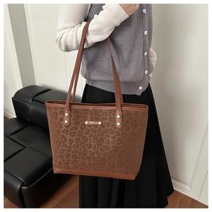 Detailed close-up of brown leopard print tote bag with gold metal fashion nameplate