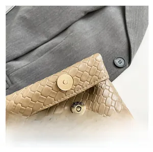 Detail of high-texture embossed leather handbag featuring a round golden magnetic closure