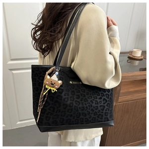 Detail of leopard print tote bag with gold metal logo and cute plush bear keychain