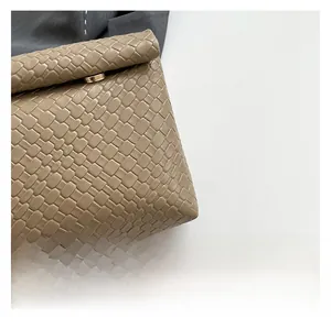 Close-up of beige woven PU leather texture with a gold magnetic clasp on an evening bag