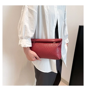 Detail of burgundy woven leather clutch bag with minimalist texture and fold-over flap