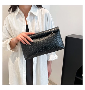 Dettaglio di una pochette in pelle intrecciata nera che mostra la trama e il design piegato