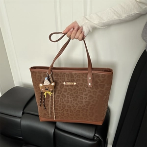 Leopard print tote bag with gold logo and cute bear pendant shown in lifestyle setting