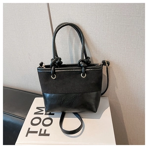 Detail einer schwarzen Beuteltasche mit Wildleder- und Glattlederstruktur und Knotengriff