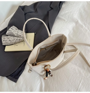 Gros plan sur l'intérieur d'un sac cabas beige avec poche zippée et breloque perlée