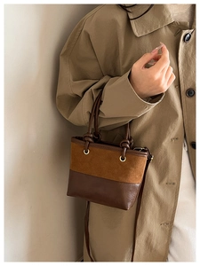 Close-up detail of vintage bucket bag with dual-tone brown textures and golden eyelets