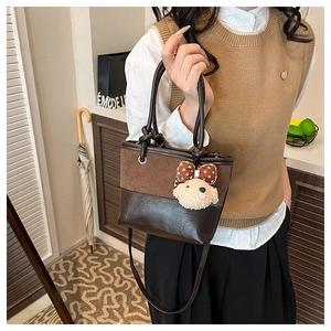 Detail of suede patchwork handbag with a cute dog charm and polka dot bow accessory