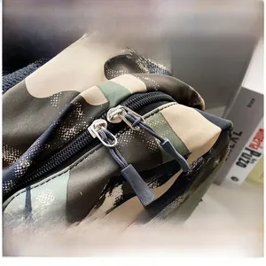 Detail display of a smooth dual metal zipper with pull cords on a camo nylon backpack