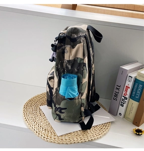 Detail view of camouflage backpack side pocket with blue umbrella and cute bear charm
