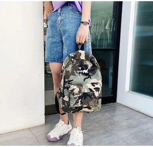 Outdoor view of a durable camouflage backpack with front zipper pocket on model
