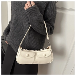Détail d'un sac à bandoulière blanc crème avec deux poches à rabat et une sangle à chaîne