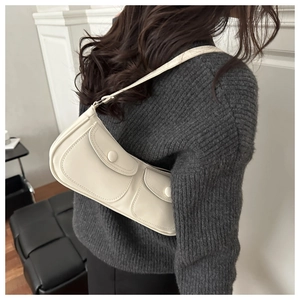 Détail d'un sac sous le bras minimaliste crème avec deux poches à rabat à l'avant