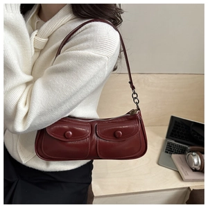 Détail du sac baguette en cuir verni bordeaux avec doubles poches à rabat avant