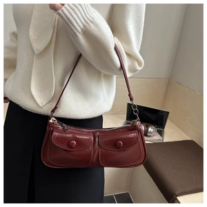 Detail of dark red glossy leather baguette bag with double front buckle pockets