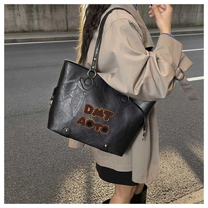 Détail du sac fourre-tout noir en PU avec broderie peluche marron café et anneaux dorés