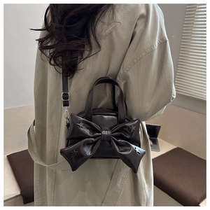 Dettaglio mini borsa a tracolla marrone scuro con grande fiocco e borchie a stella