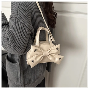 Dettaglio della borsa beige a tracolla con grande fiocco e borchie metalliche a stella