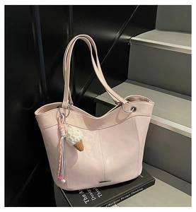 Detail of pink faux leather tote bag featuring metal logo plate and ice cream pendant