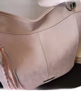 Close-up of pink tote bag with matte texture, silver metal bar and braided pendant