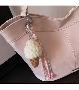 Handmade crochet ice cream charm with knitted strap on a pink leather shoulder bag