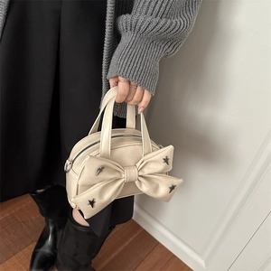 Mini sac à main crème avec nœud et clous en étoile argentés, vue élégante portée main