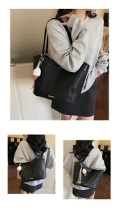 Detail of black leather tote bag with metal logo plate and cute ice cream charm pendant