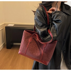 Detail of burgundy leopard embossed tote bag with smooth leather trim and handle