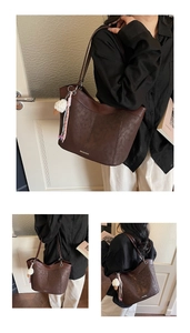 Detail of dark brown faux suede tote bag with slim shoulder straps and metal hardware