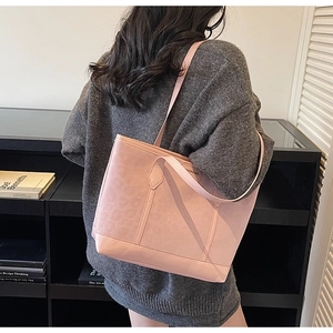 Detail of pink tote bag showing subtle leopard texture and metallic fashion emblem