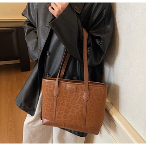 Leopard print tote bag detail showing suede texture and dual shoulder straps on a model