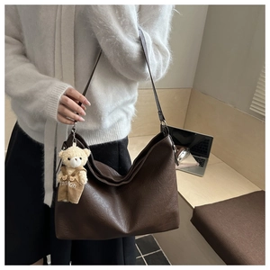Detail of vintage brown tote bag featuring a cute teddy bear charm for daily use
