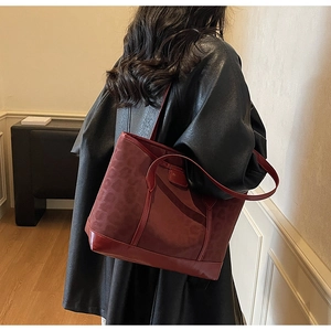 Detail view of burgundy leopard print tote bag with faux suede texture on model side profile