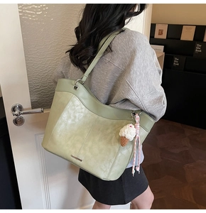 Detail of light green tote bag with silver bar and plush ice cream pendant charm