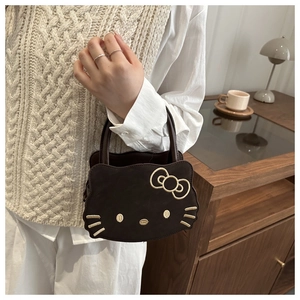 Detailed embroidery of cartoon cat features on a dark brown suede textured handbag